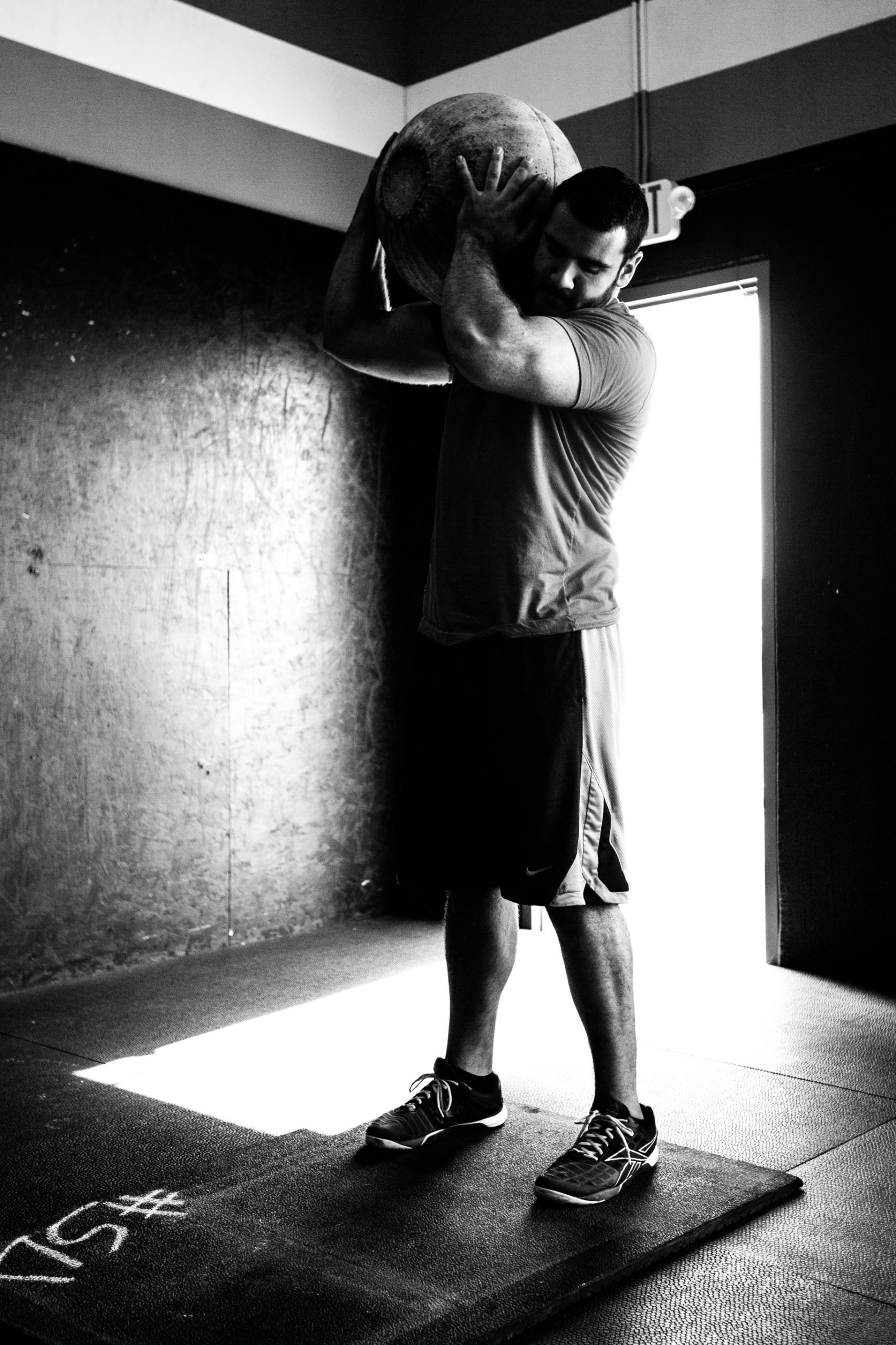 Black and White Photo: Athlete Lifting Heavy Medicine Ball in Gym