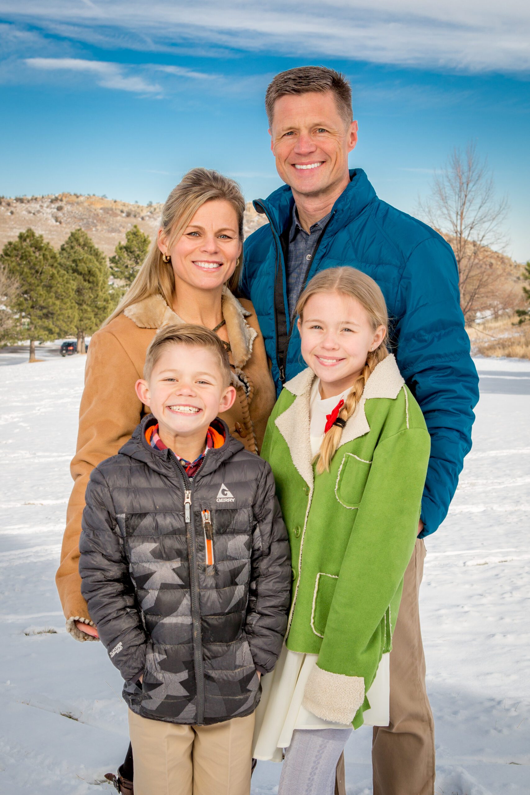 Family of four smiling in a snowy landscape