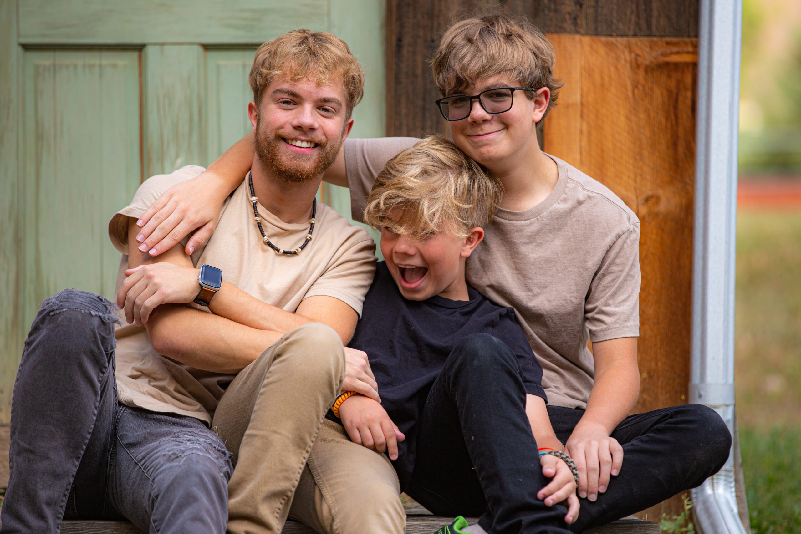 Three brothers sharing a joyful moment outdoors.