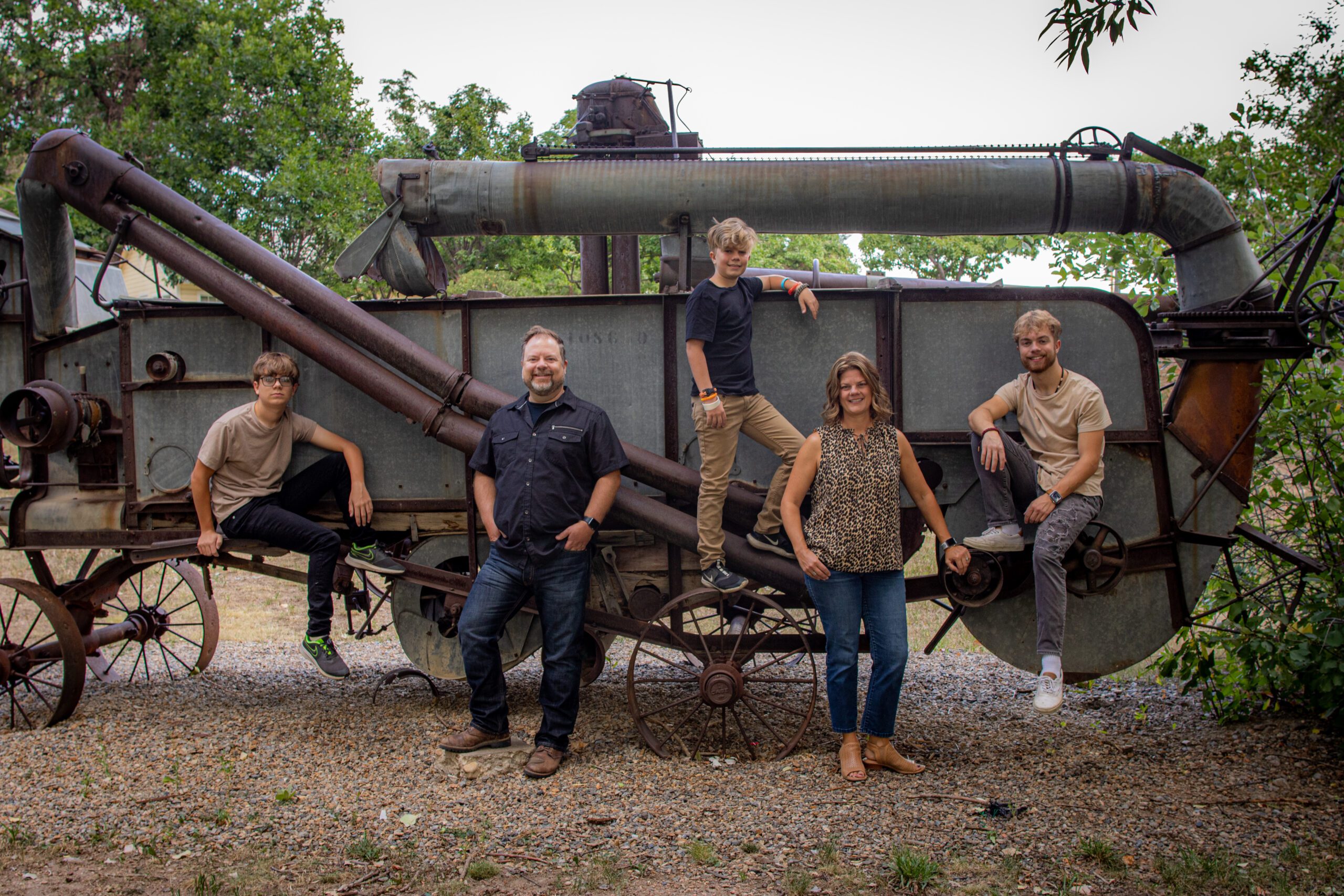 Family of five posing with an antique threshing machine