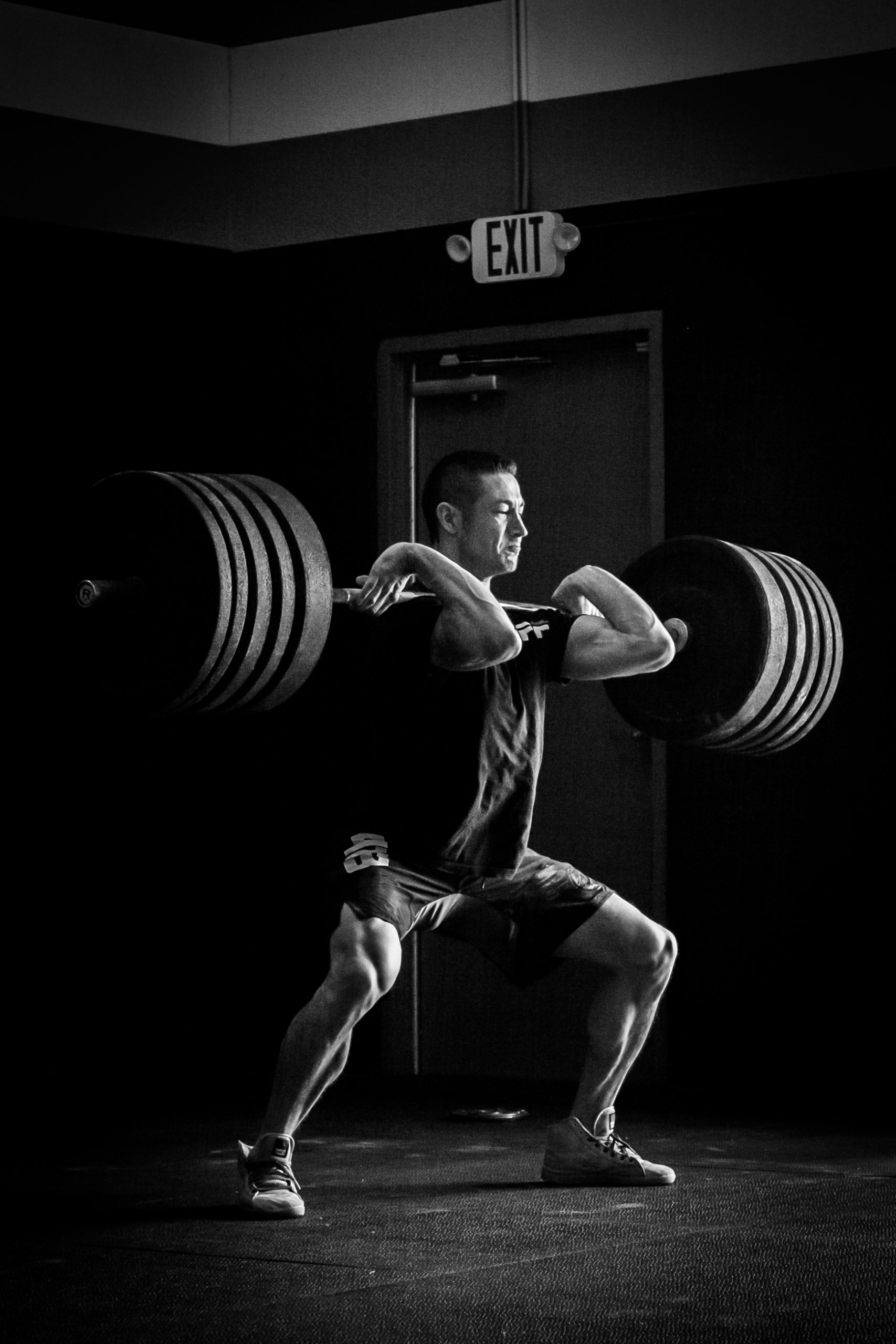 Focused Athlete Doing Barbell Power Clean in Monochrome CrossFit Gym Setting