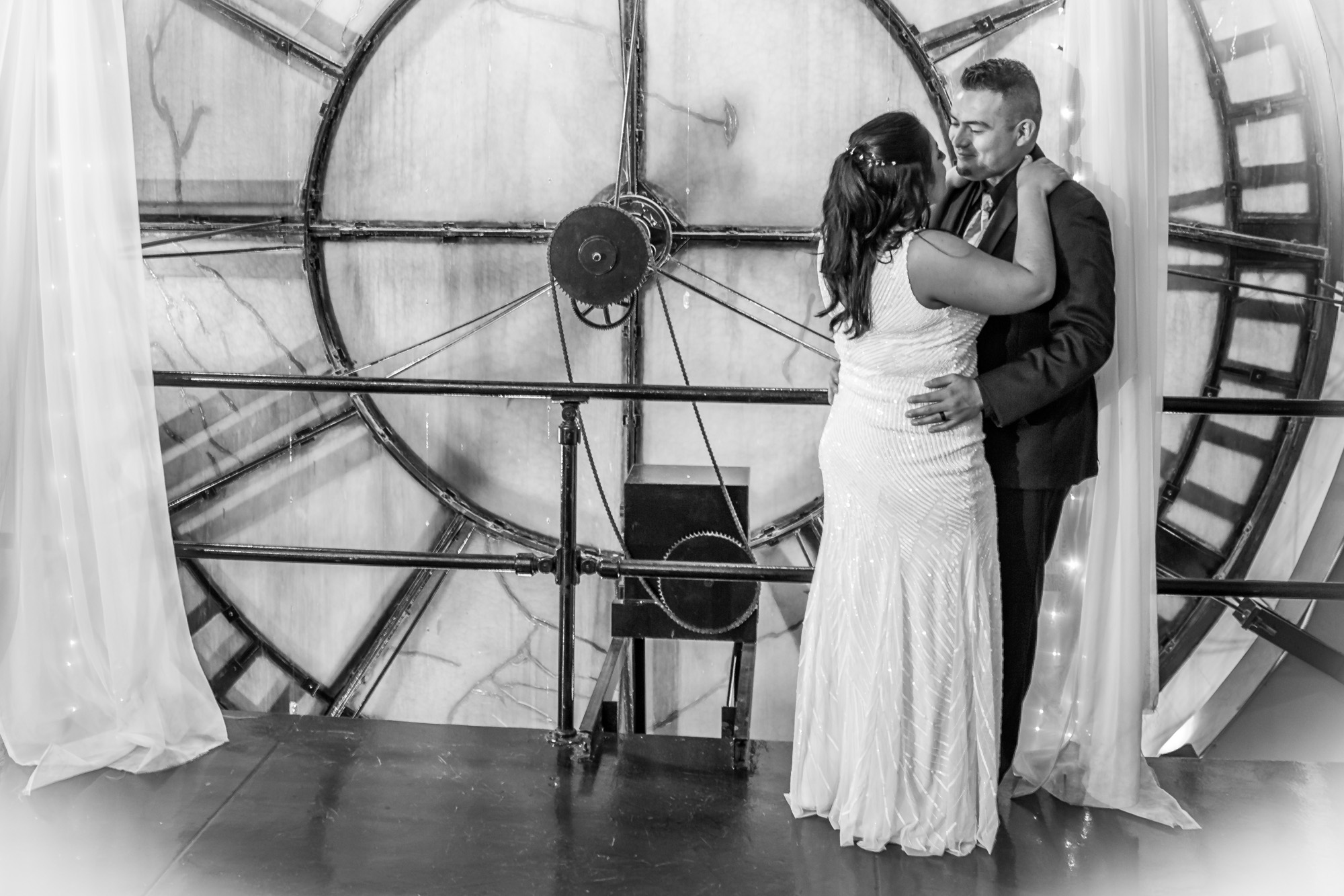 Bride and Groom Sharing a Dance in Front of a Large Circular Window, Captured in a Timeless Black and White Photo.