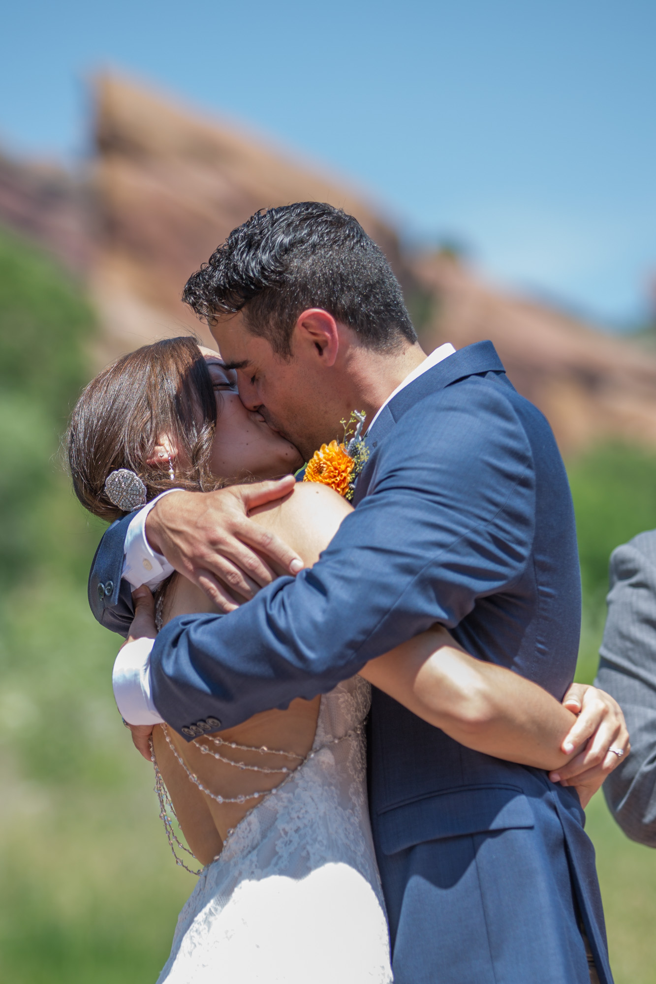 Bride and groom sharing a heartfelt kiss with a scenic rocky landscape in the background on their wedding day