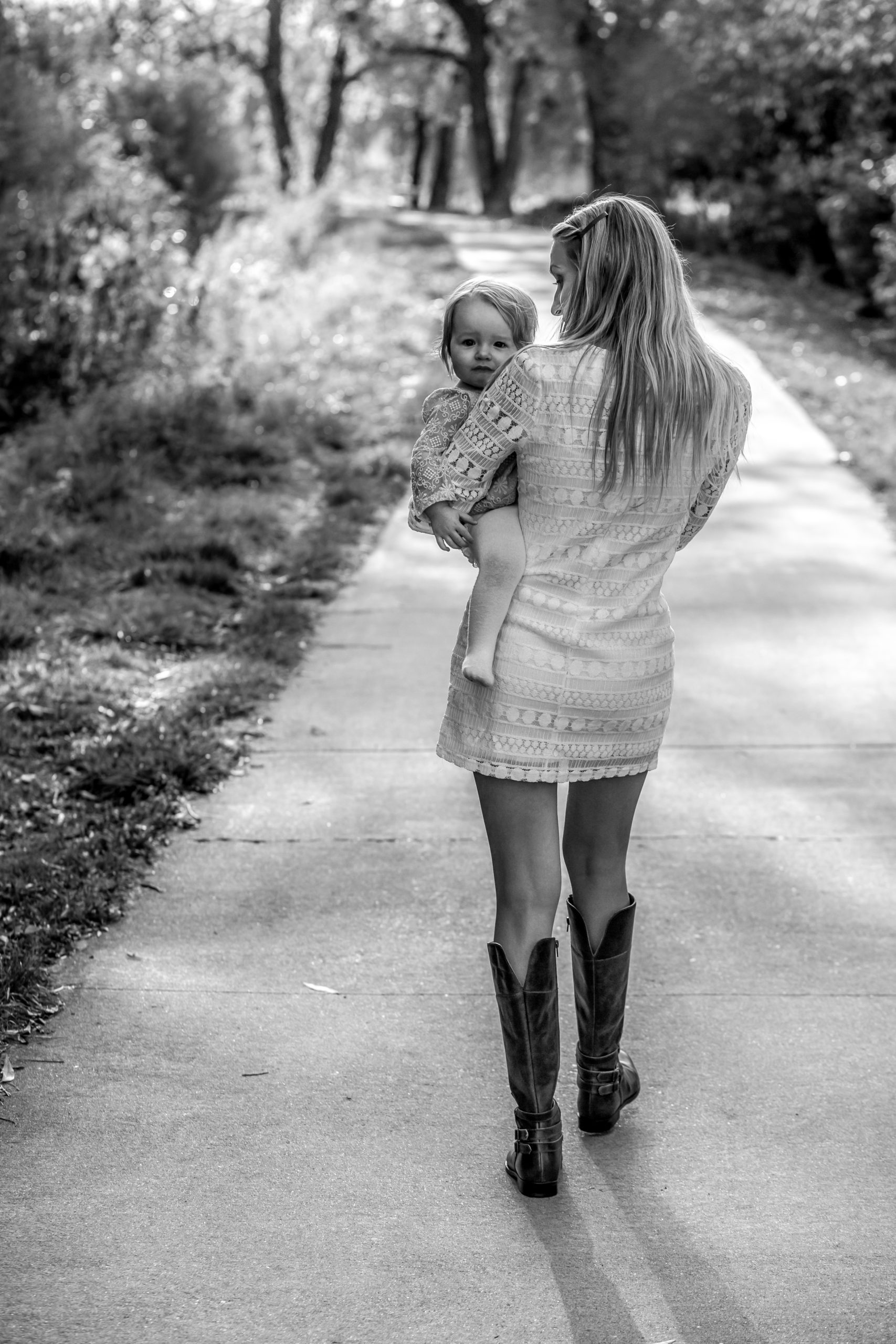 Mother carrying her child on a sunlit pathway