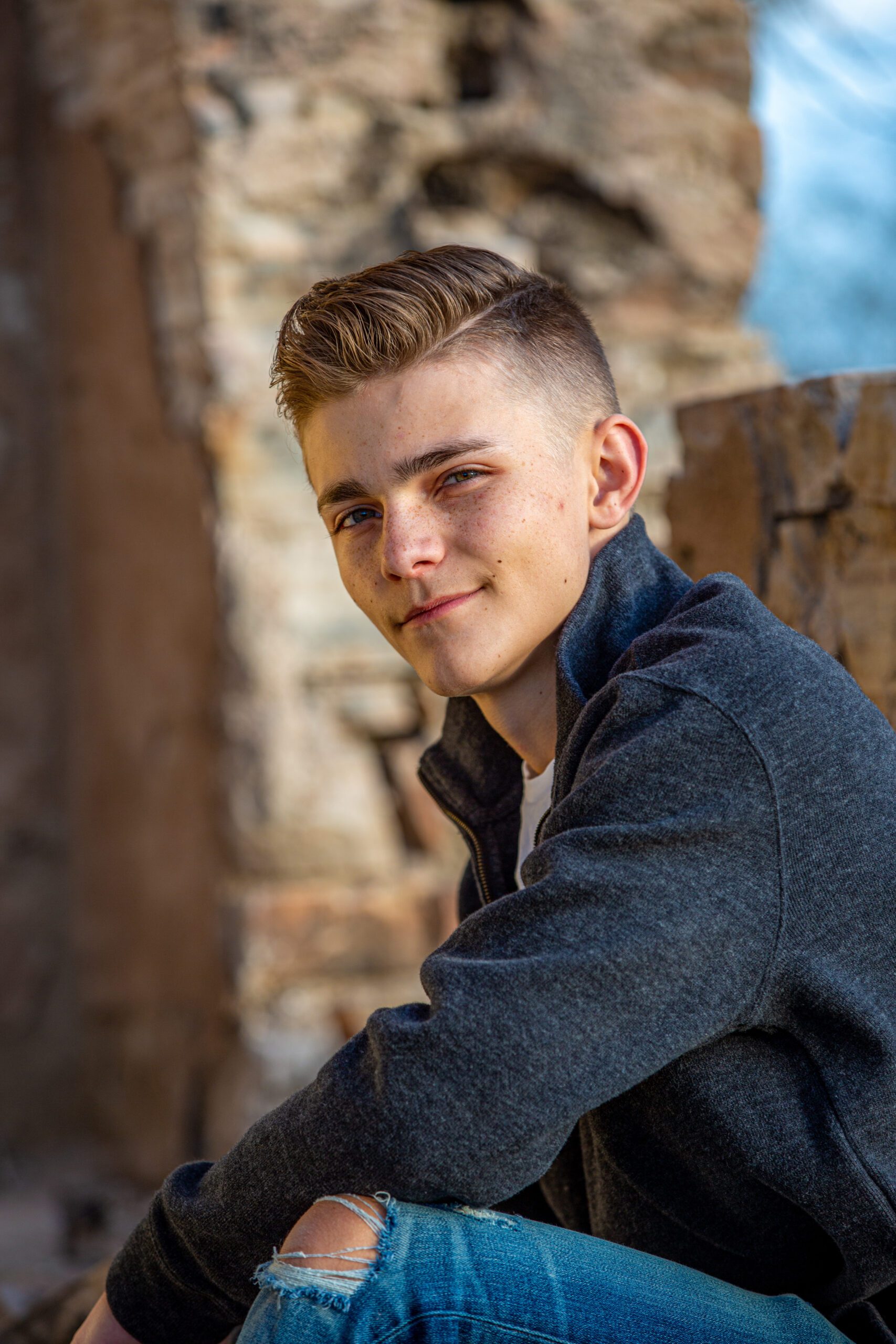 Senior man with a trendy haircut and casual jacket seated in an urban backdrop, looking at the camera