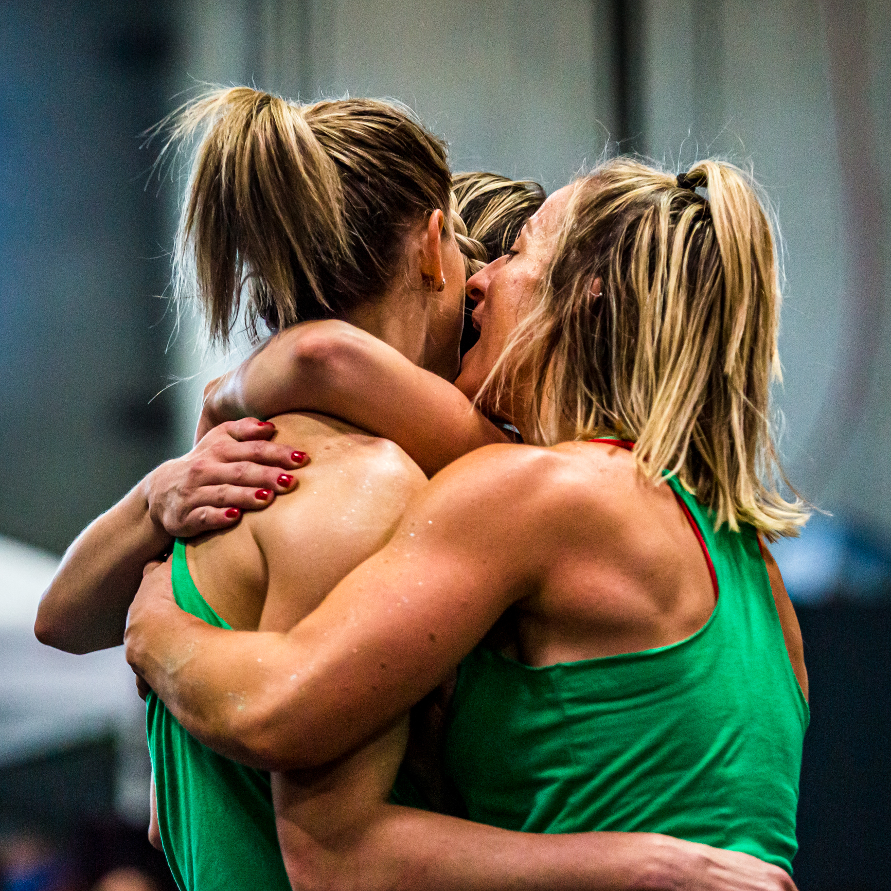 Emotional Embrace Between Three Female Athletes in Green, Celebrating Teamwork and Success.