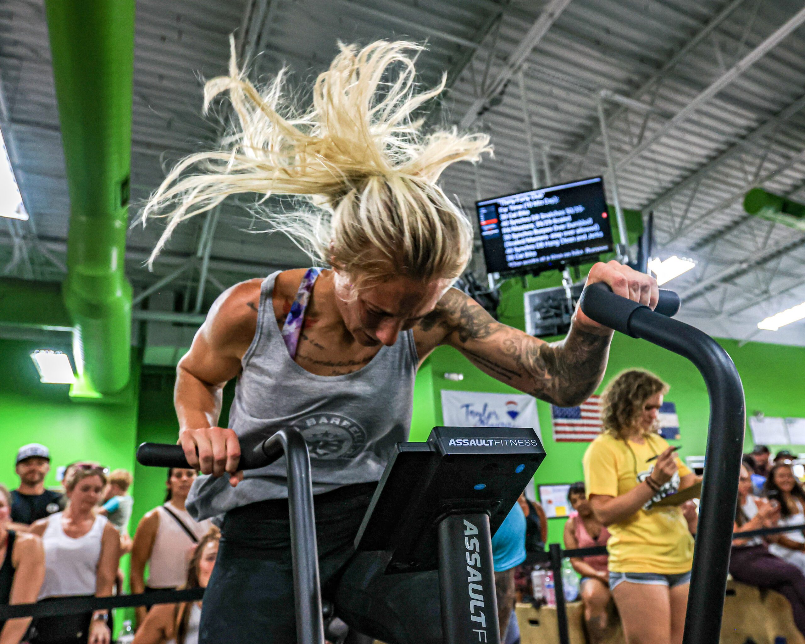 Female Athlete With Tattoos on Air Bike in CrossFit Gym