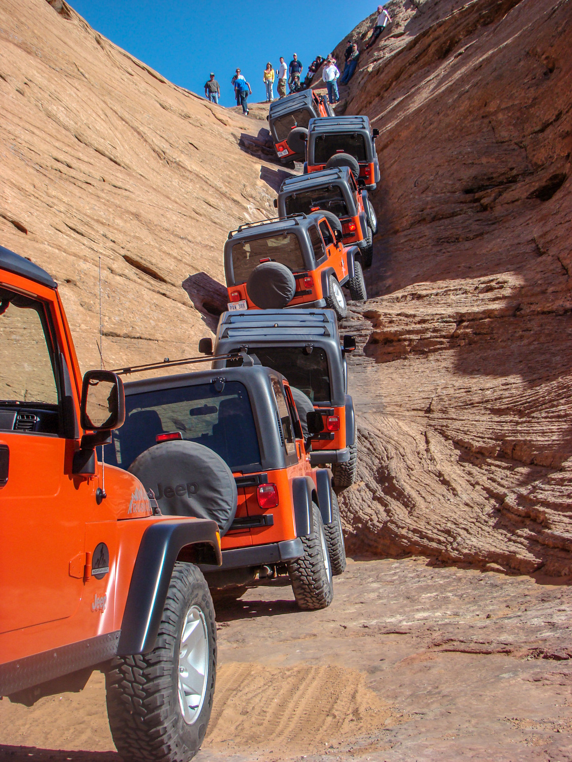 A 'visual timelapse' of an orange Jeep navigating the steep, rocky incline of the Escalator obstacle on Hell's Revenge Trail in Moab, Utah.