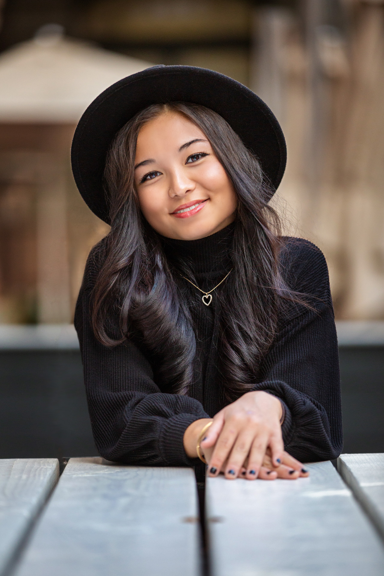 Female high school senior smiling and relaxing in a cute hat in an urban environment during a photoshoot.