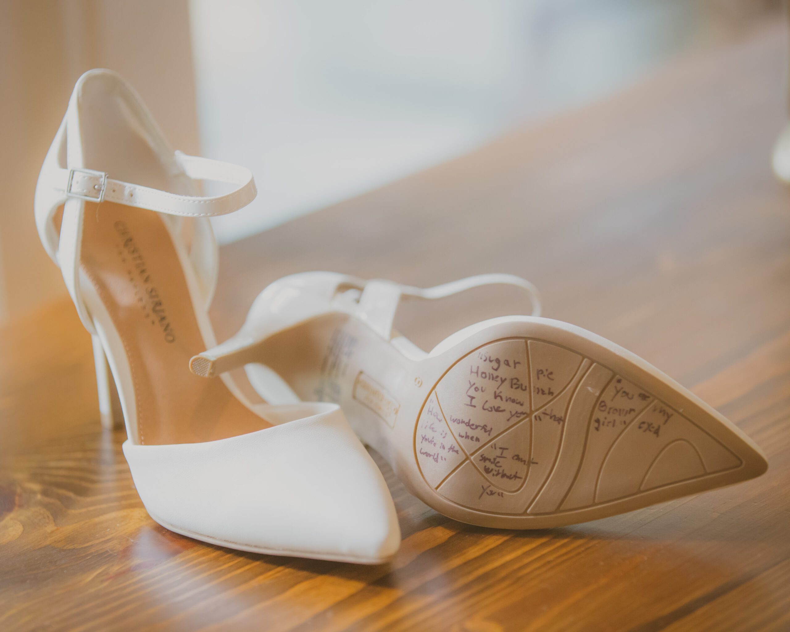 Bride's white heeled shoes with handwritten messages on the soles