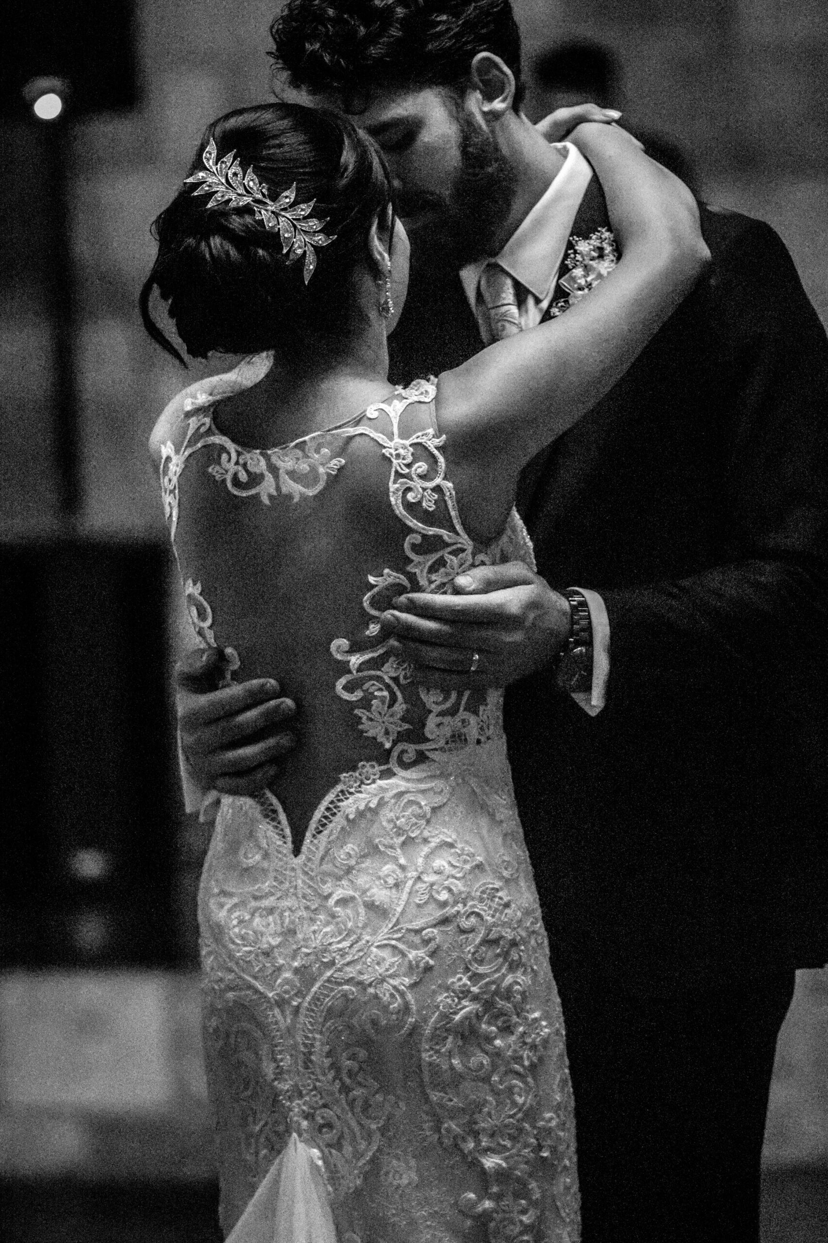 Bride and groom in a heartfelt dance, bride's lace dress and hairpiece in detail, in black and white