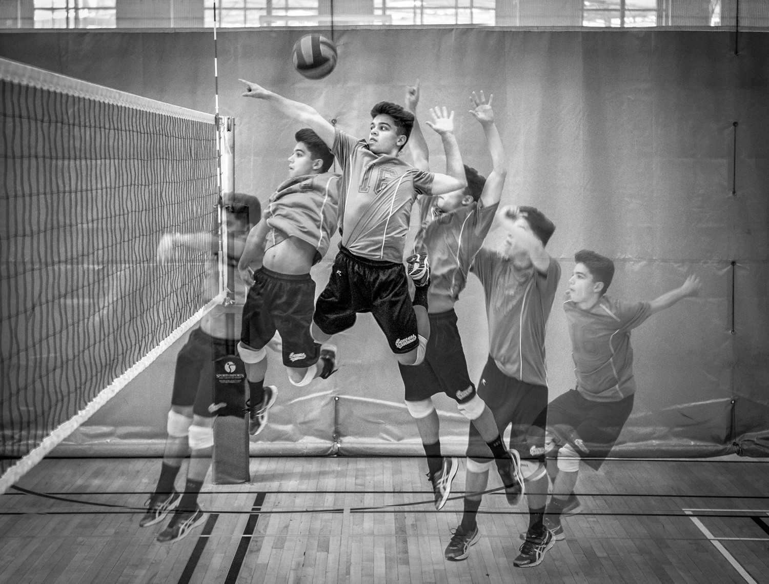 Composite image of a male volleyball player jumping to hit a ball over the net