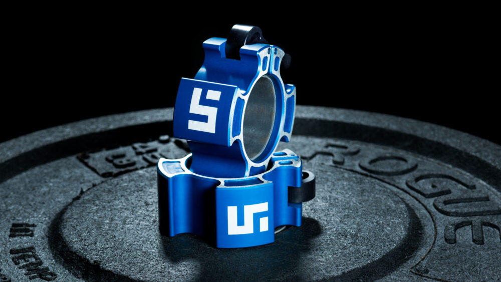 Studio shot of unique and customized barbell collars on a Rogue weight plate, highlighted by lighting to emphasize their form and detail.